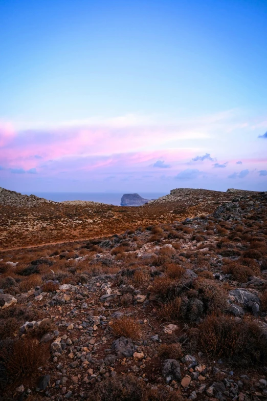 there is a field of rocks and dirt by the water