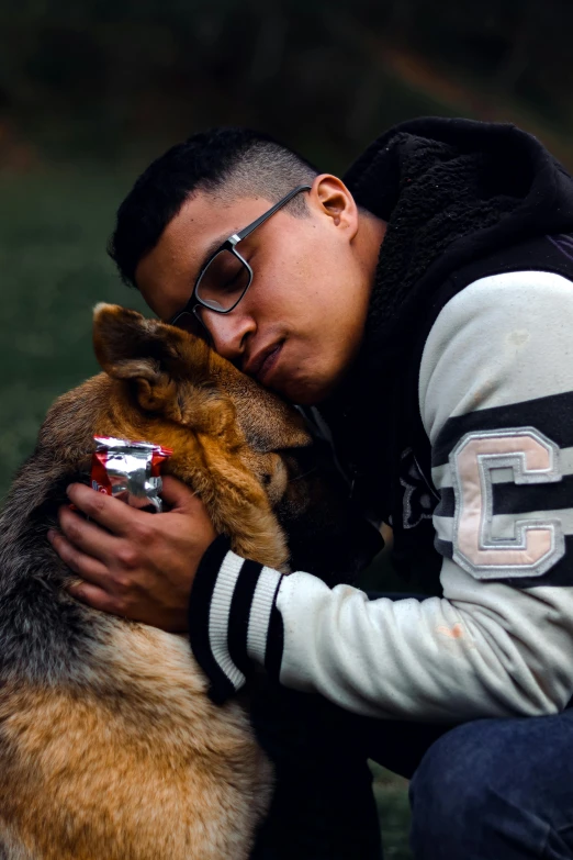 a man hugging his dog who is holding a tinfoil pack