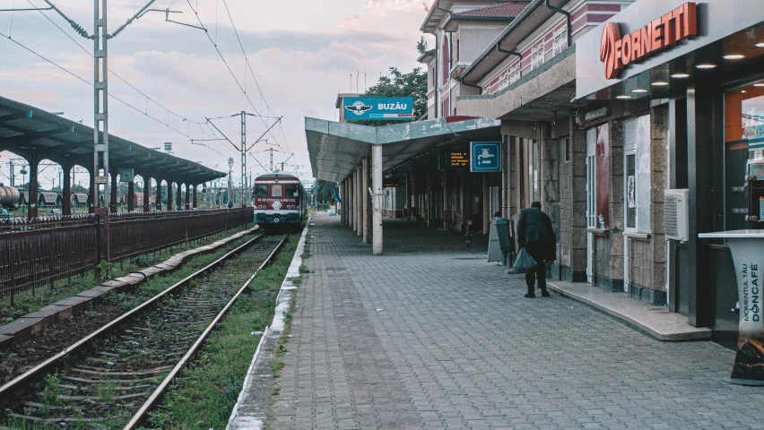 two train tracks near a train station with people on the platform