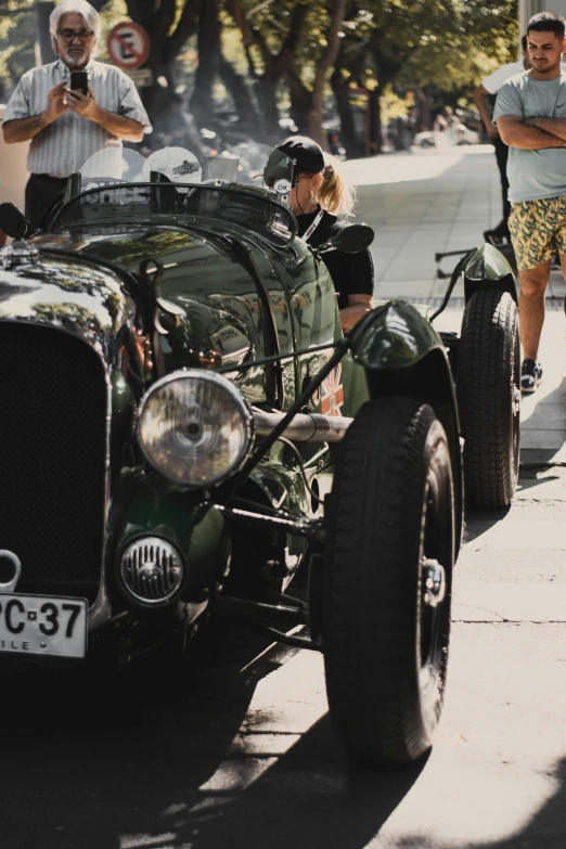 old timey car being prepared by group of people