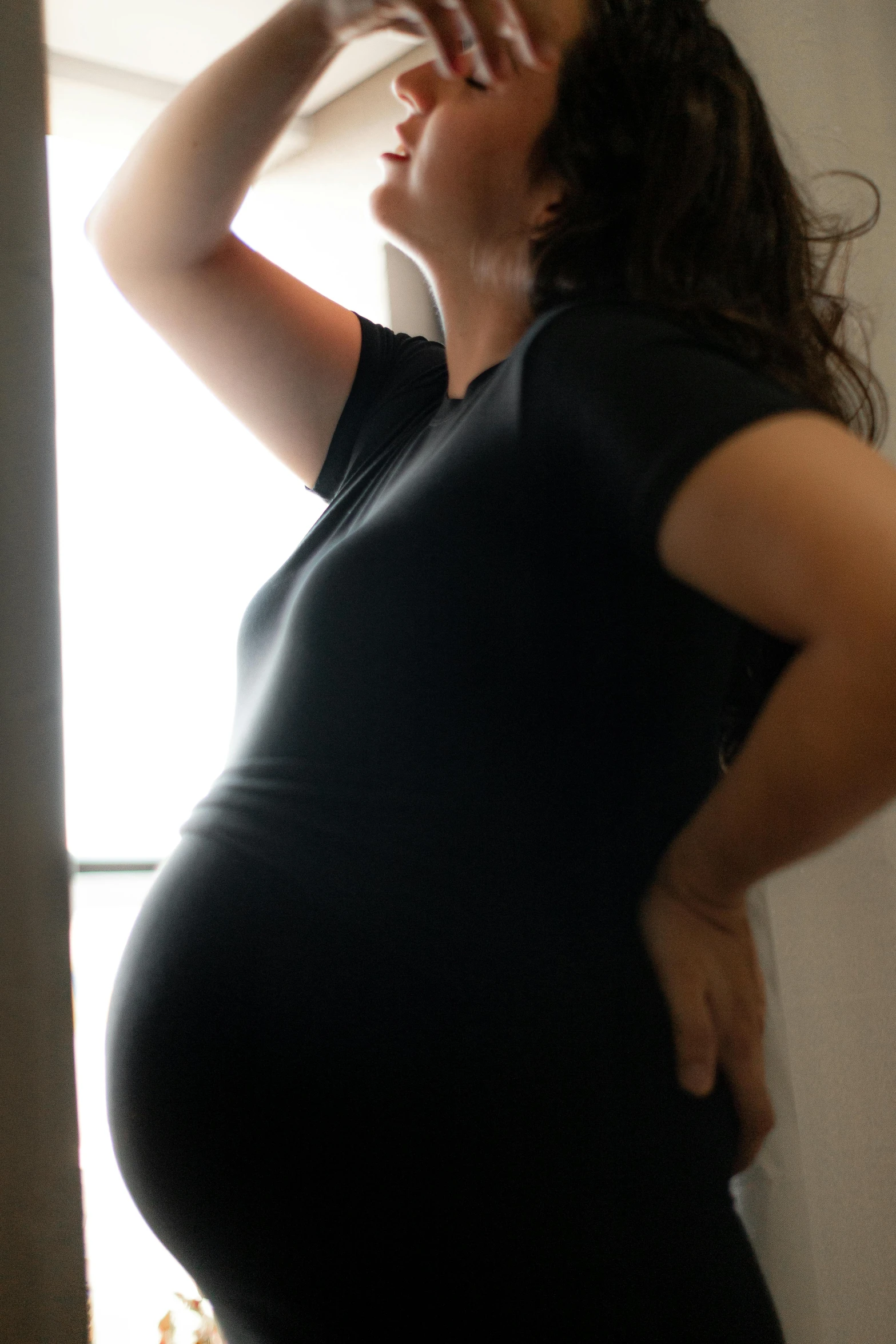 the pregnant woman stands in a room with her hands on the head