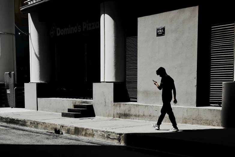 person walking down the sidewalk in the shadows