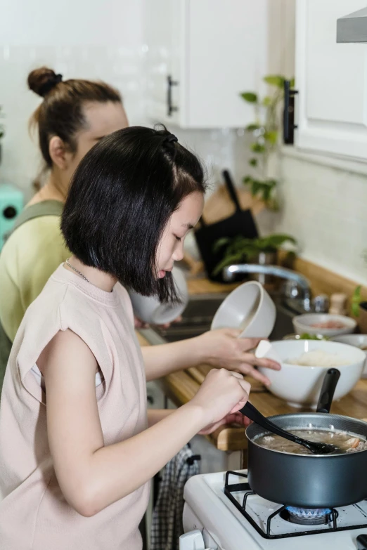 a woman in pink is preparing food on a stove