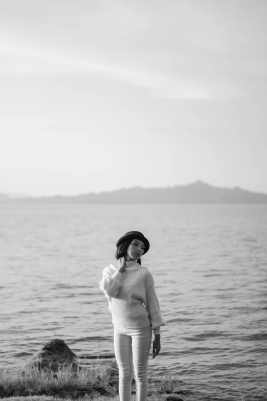 a woman standing next to the ocean on the shore