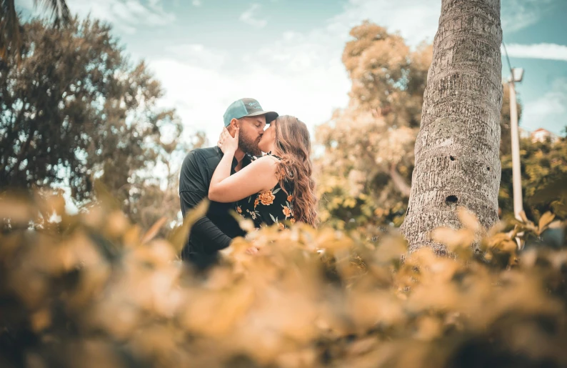 a couple poses for the camera in front of trees