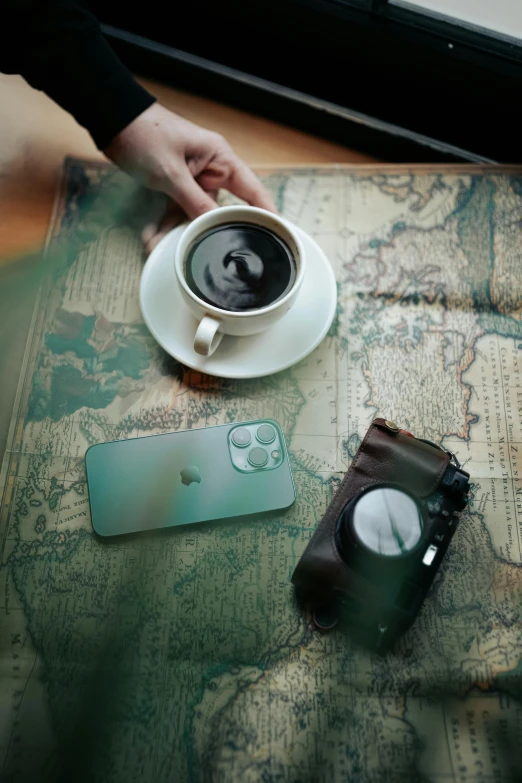 a person holds a coffee cup over a map