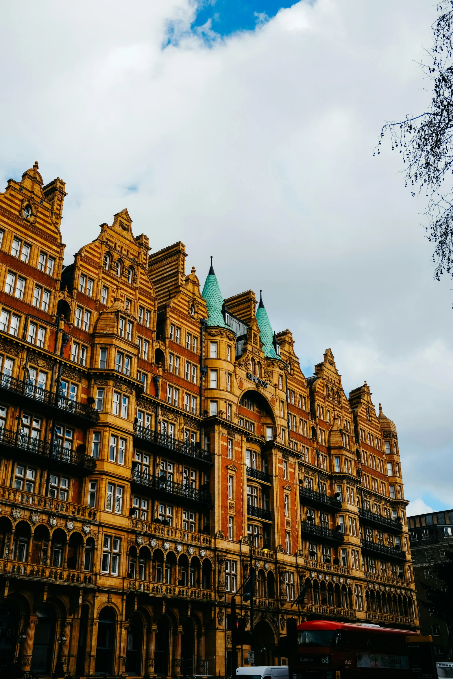 large brown buildings with green towers against a cloudy sky