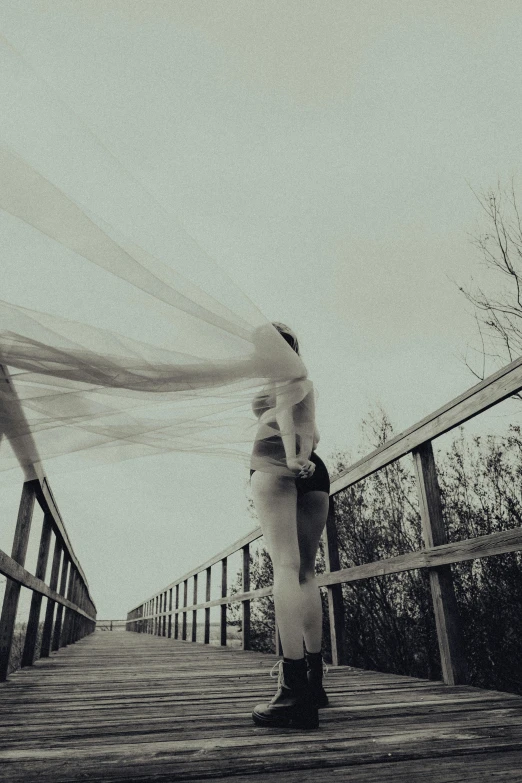 a black and white po of a couple kissing on a bridge