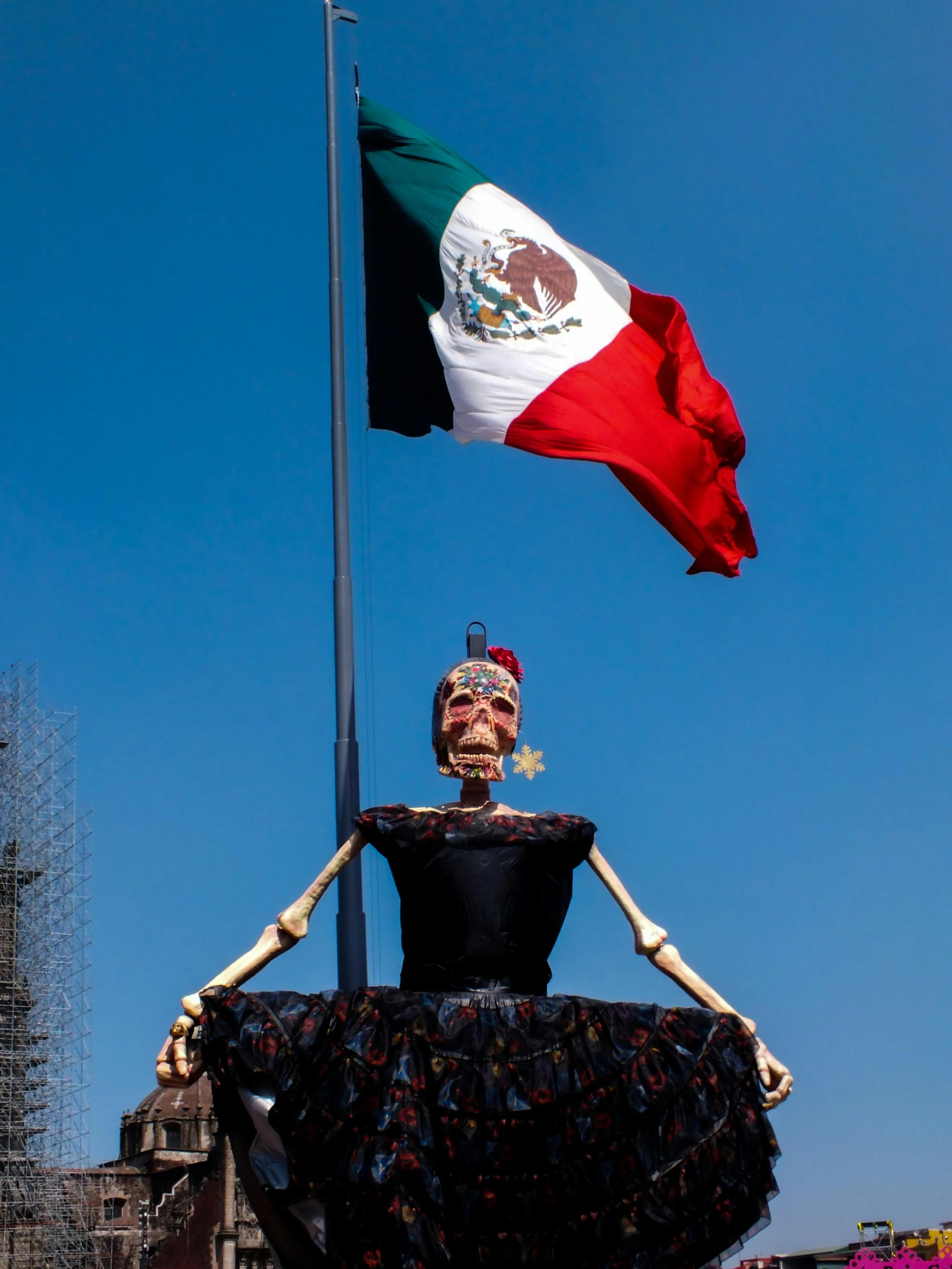 a sculpture wearing a dress and sitting on top of a flag pole