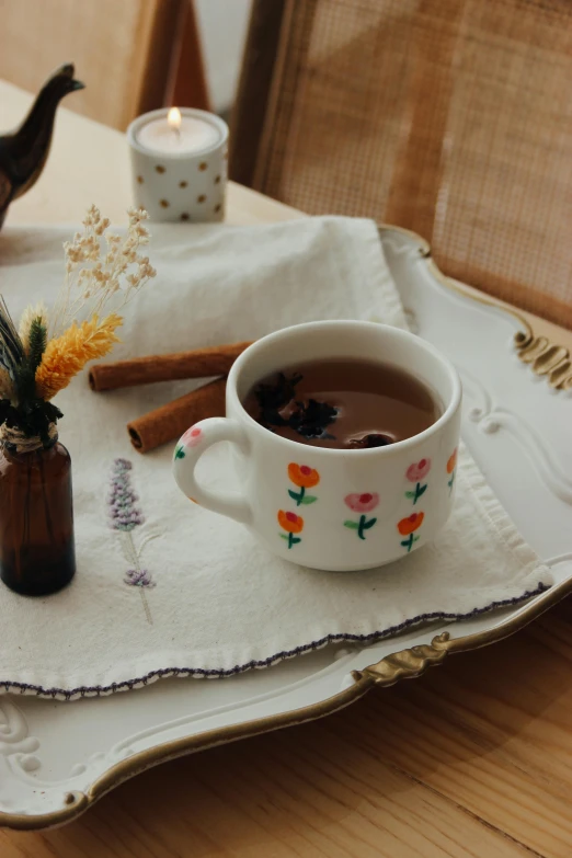 a white tea cup sitting on top of a tray next to a tea light