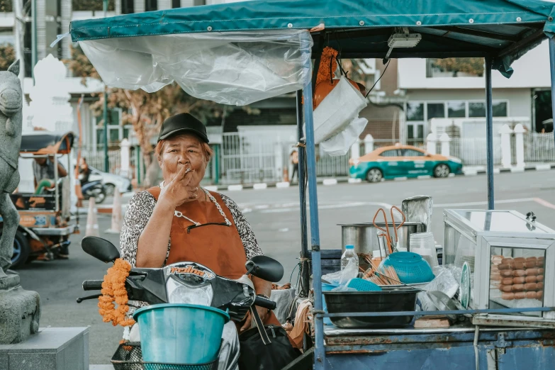 the man is standing at the street vendor talking on his phone