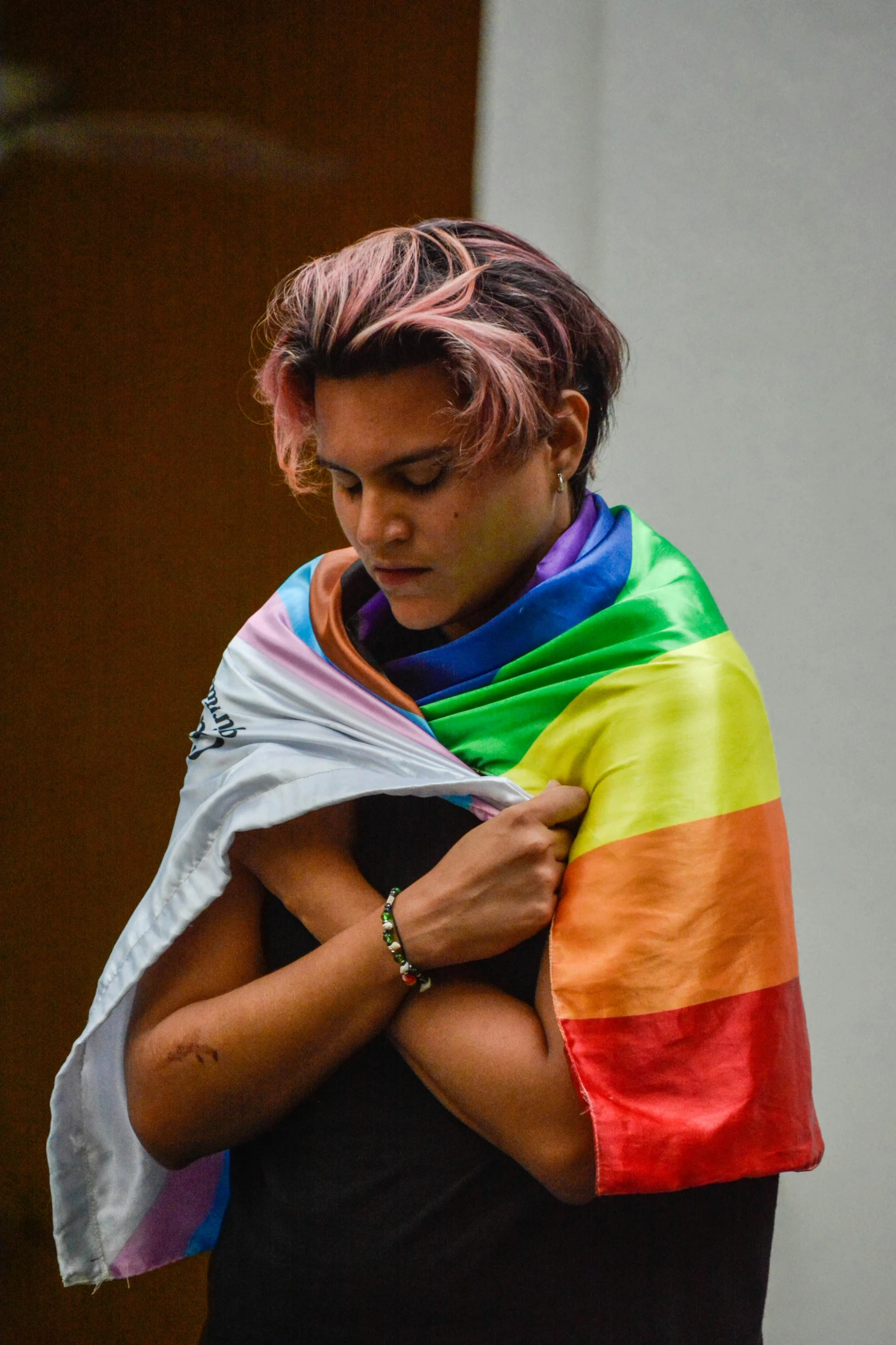 a woman is holding a rainbow colored scarf