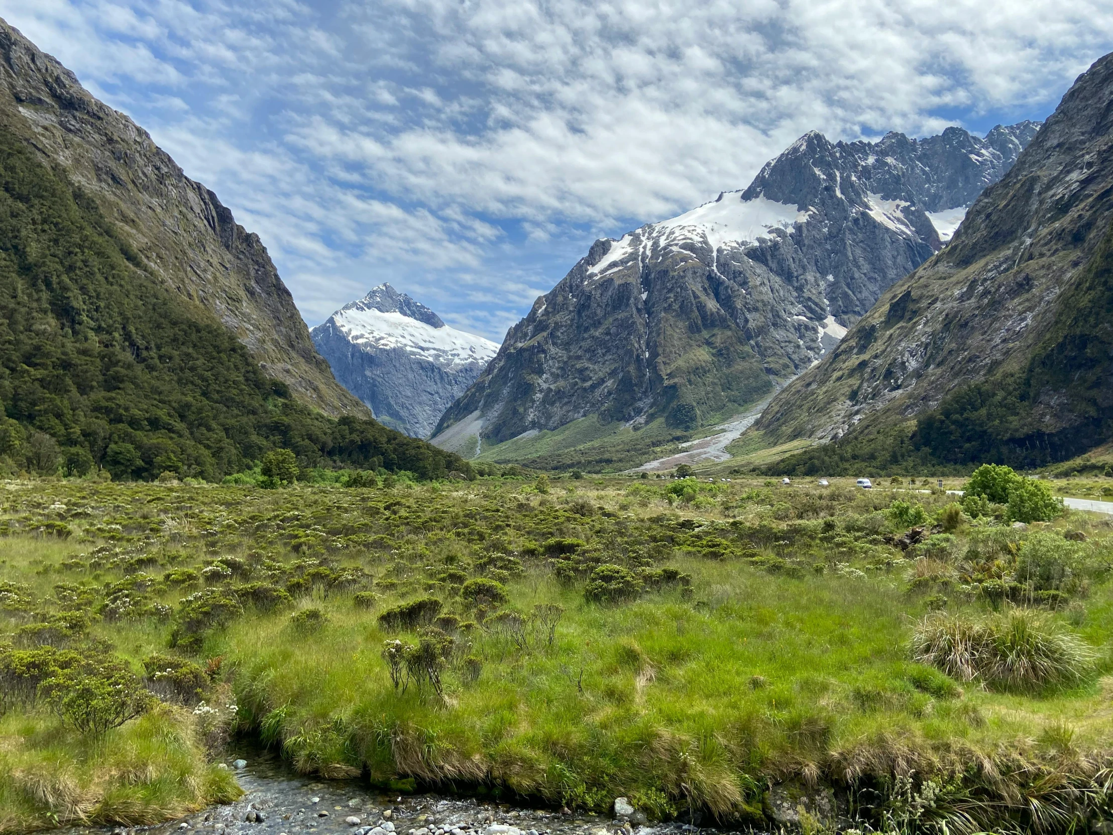 a mountain range with water and grass on it