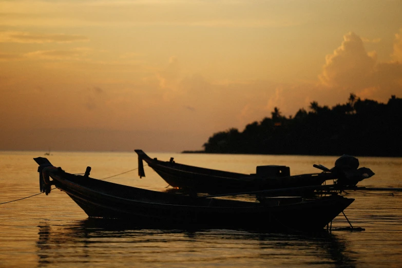 two boats sit in a large body of water at sunset