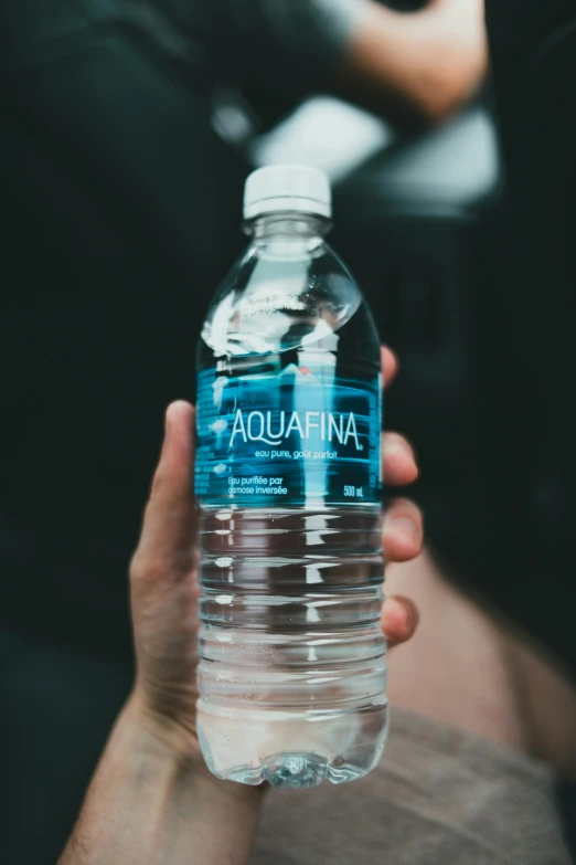 a person is holding a bottled bottle of aquafina water