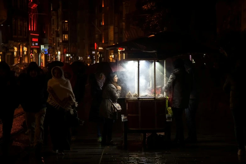 people standing around a vendor at night with lights on