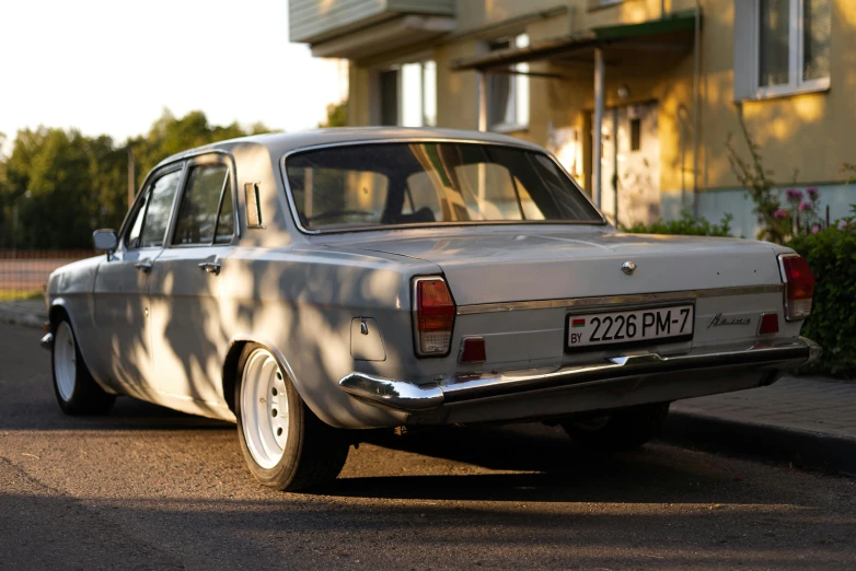 a silver old style car is parked in front of the house