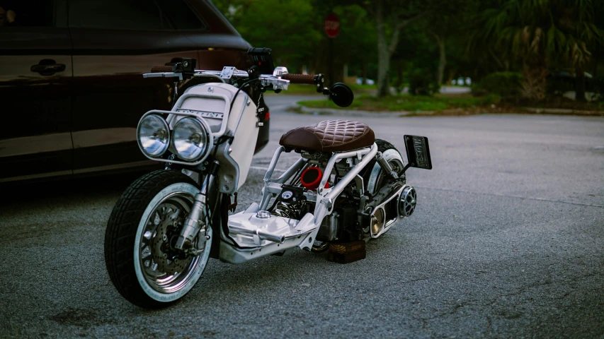 a silver motorcycle parked next to a car on the side of the road