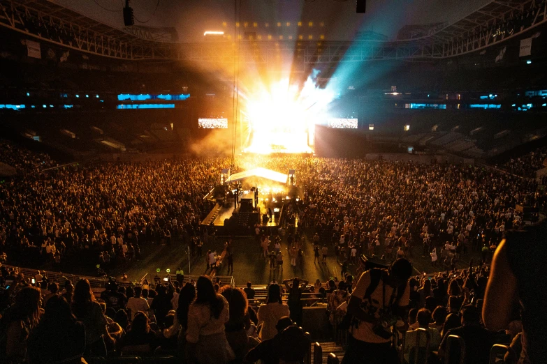 a large crowd watches a concert with bright lights