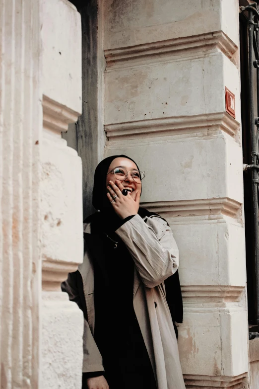 a smiling woman leans against a building's wall