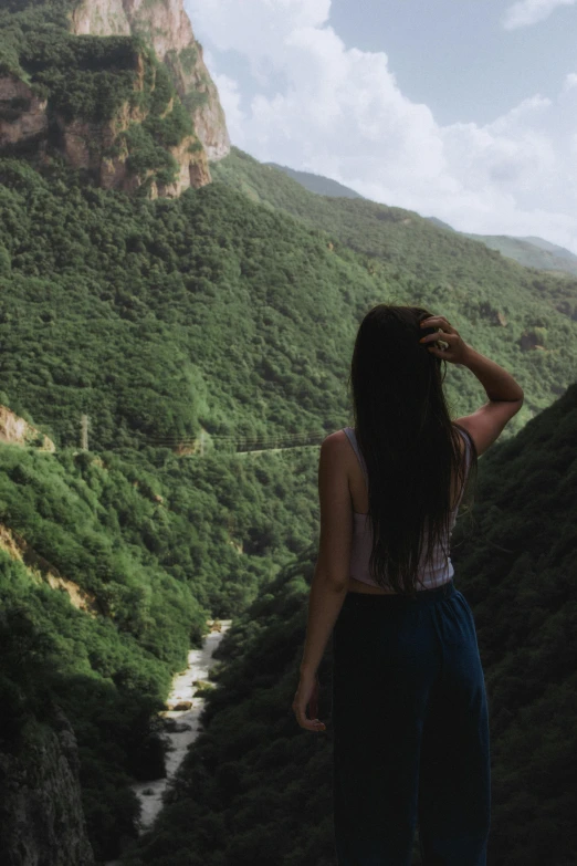 a young woman standing in front of a mountain