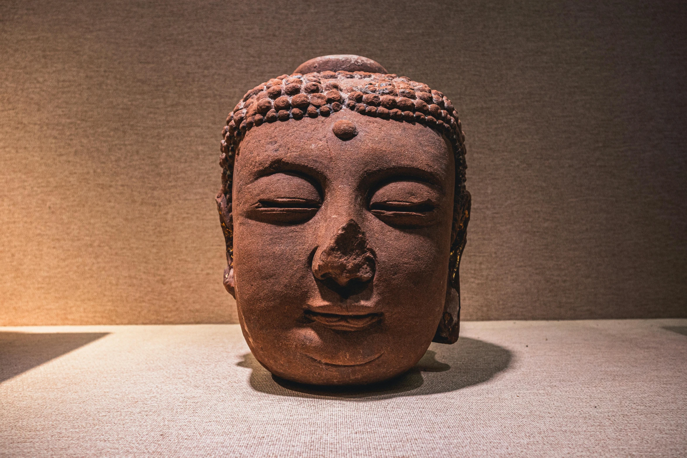 a clay statue of buddha head that is standing on a table