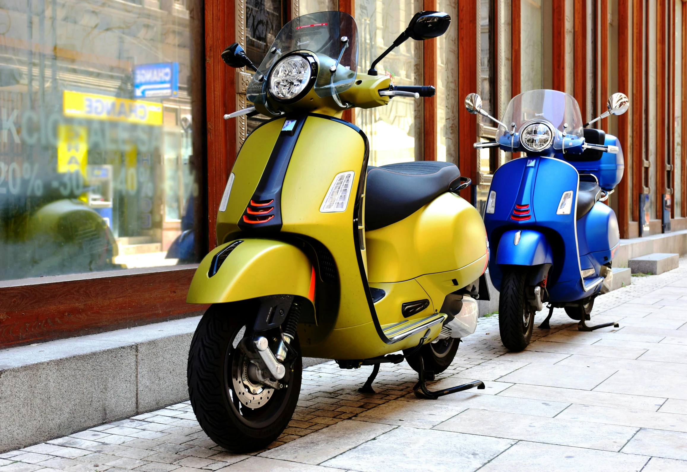 two colorful scooters sitting on a sidewalk outside