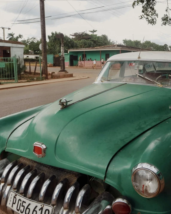 an old vintage green car parked in front of a house