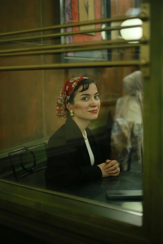 a woman looks in the mirror at a desk with a laptop computer