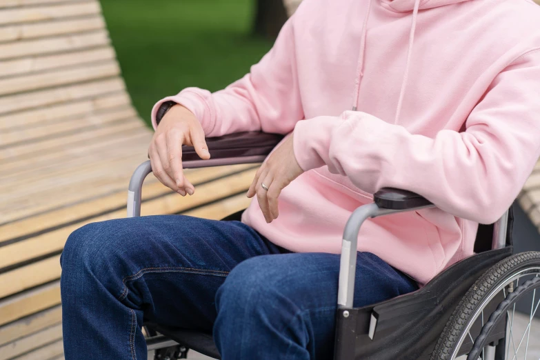 an older person wearing a pink hoodie sitting on a bench