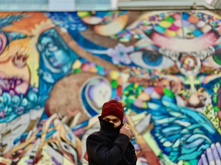 a woman in black hoodie wearing mask on her face near wall