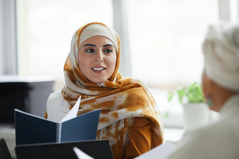 a woman in a hijab smiles while reading