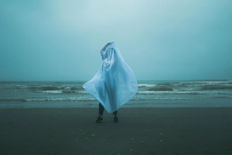 person wearing a blue cloth in the ocean under a blue cloudy sky