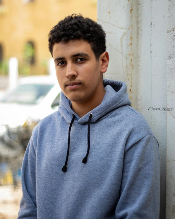 a young man wearing a hoodie and looking at the camera