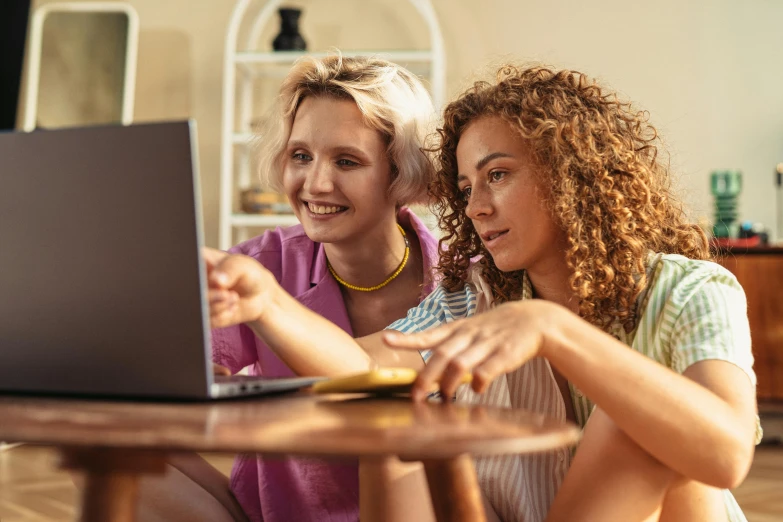 two women sitting at the kitchen table look into the laptop