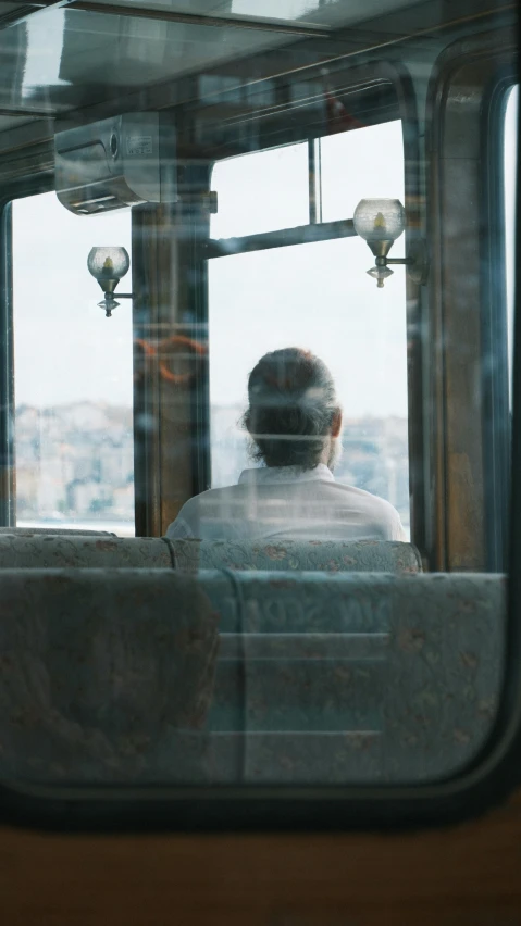 man sitting in seat next to window watching city