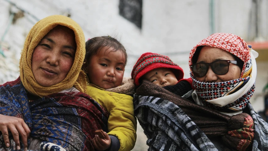 three women and a baby wearing scarves with hats