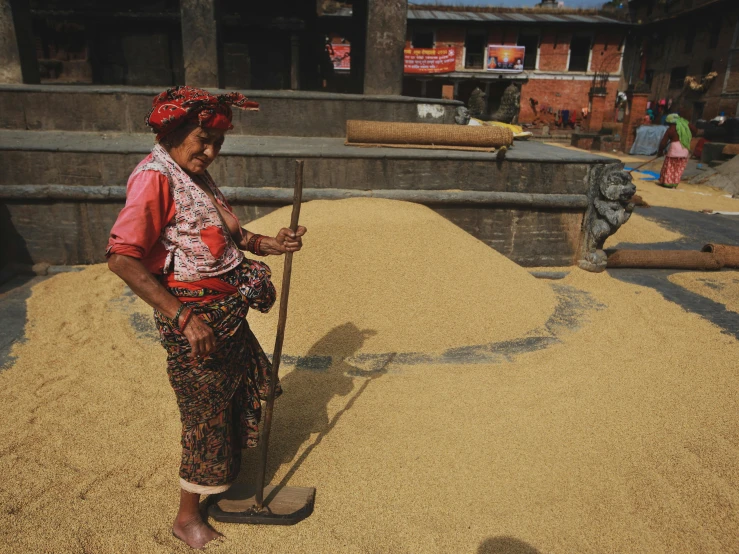 a woman with a broom is in the dirt