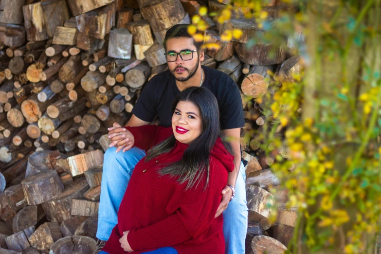 a man and a woman standing next to a pile of fire wood