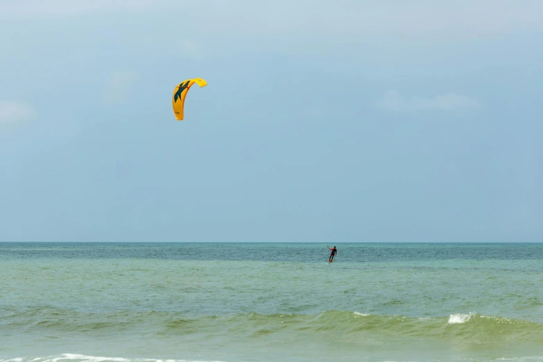 a person parasailing on the ocean with a large yellow parachute