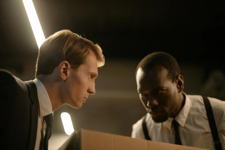 two men looking at an envelope while standing in the dark