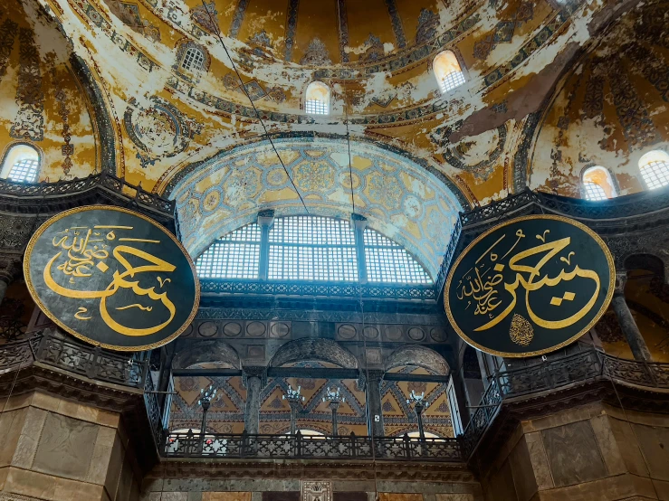 two large circular clocks with arabic writing in a ornate room