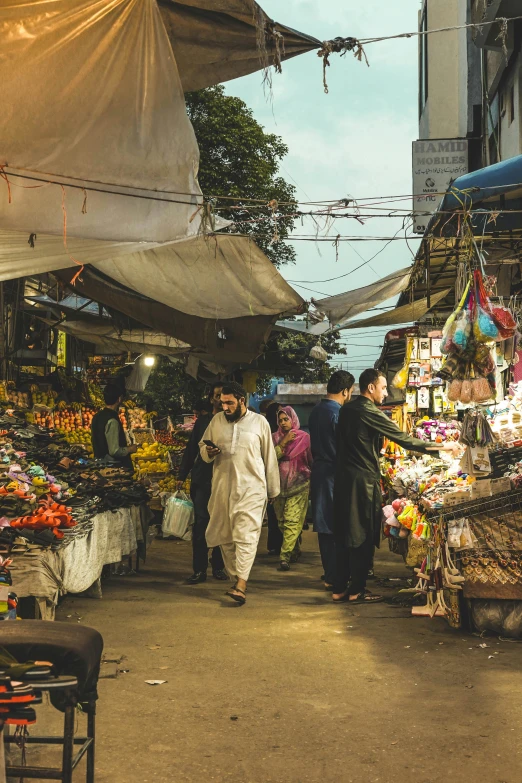 people walking down an alley way lined with various stalls