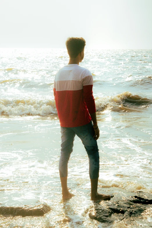 a man standing on the beach watching waves crash