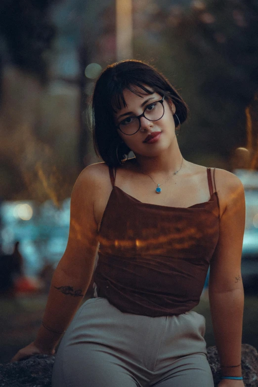 woman with glasses sitting outdoors with a cell phone