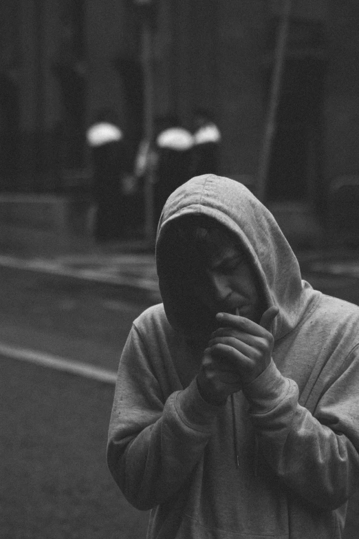 a person walking in the rain and covering their face with a hoodie