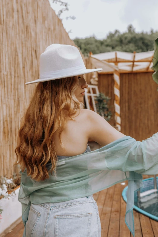 a woman in blue clothes holding an umbrella next to a wooden structure