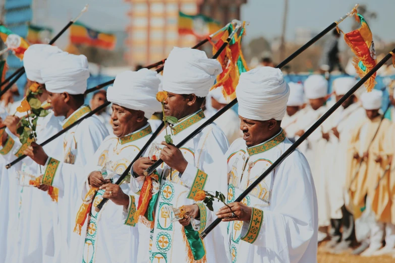 some indian men wearing bright white clothes stand with colorful flags