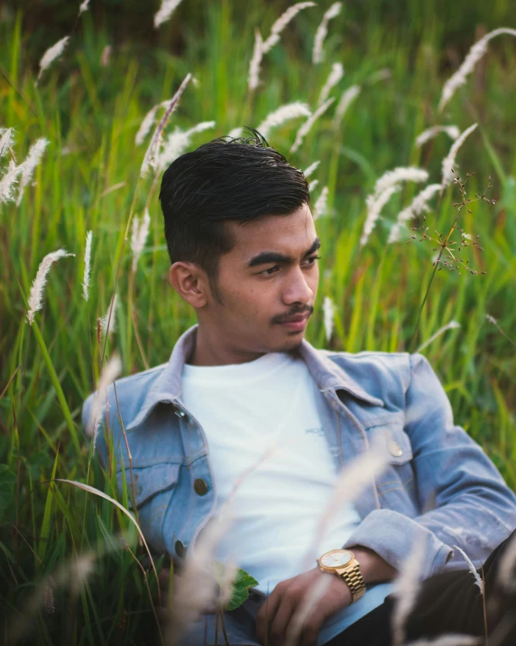 a young man sitting in a field of grass