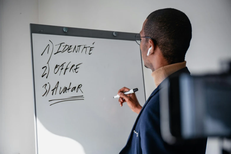 a man writing on the whiteboard in his office